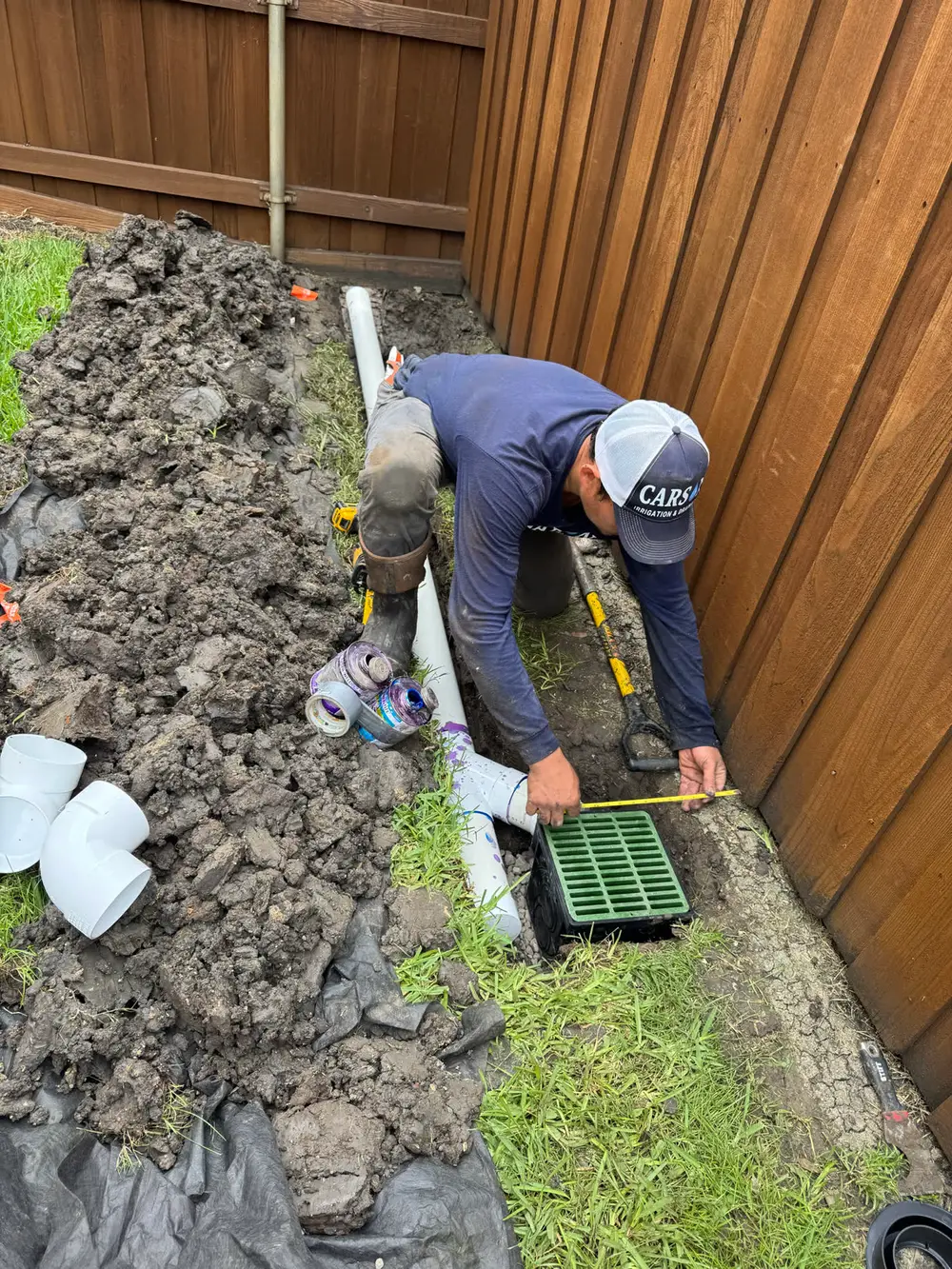 Carson tech installing catch basin drainage along fence